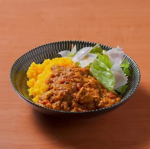 トマトの赤みがあるチキンスパイスカレー。ターメリックライスとサラダ添え