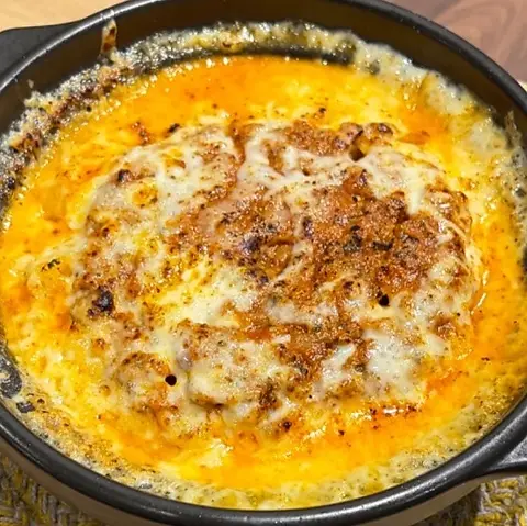 とけたチーズの縁からトマトのソースがのぞくドリア。黒い鍋のまま提供