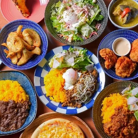 テーブルに並んだスパイスカレー、から揚げ、サラダなどの料理