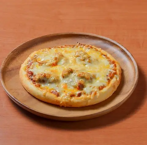 チキンとチーズが全面にのった辛口チキンスパイスカレーピザ。木の皿に
